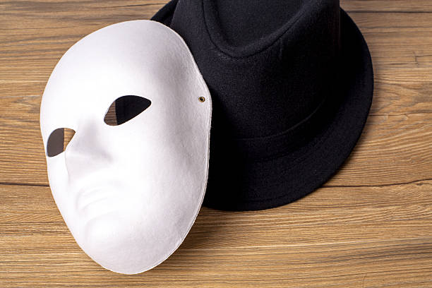 facial mask and fedora hat on table - hypocrisy imagens e fotografias de stock