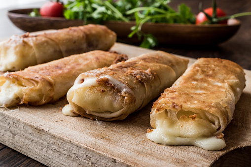 Turkish Pacanga Boregi with pastirma and cheddar (melted) cheese. / Pastirmali Borek on wooden surface