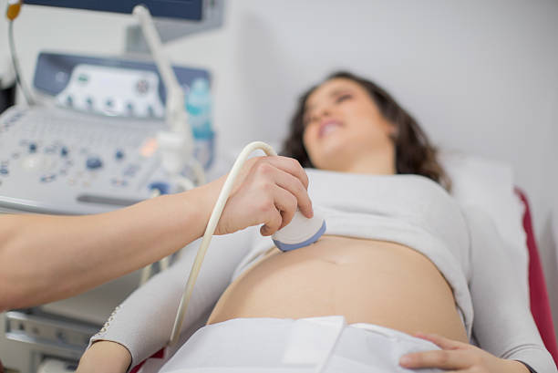 Doctor performing ultrasound on pregnant woman Doctor performing ultrasound on pregnant woman abdominal ultrasound stock pictures, royalty-free photos & images