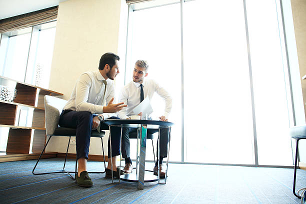istock Image of two young businessmen using touchpad at meeting. 637404552