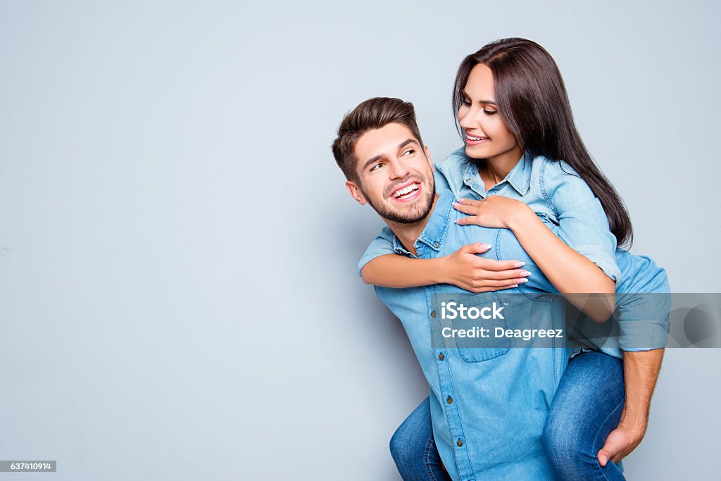 Happy  man carrying his girlfriend on the back Happy  man carrying his girlfriend on the back on gray background Boyfriend Stock Photo