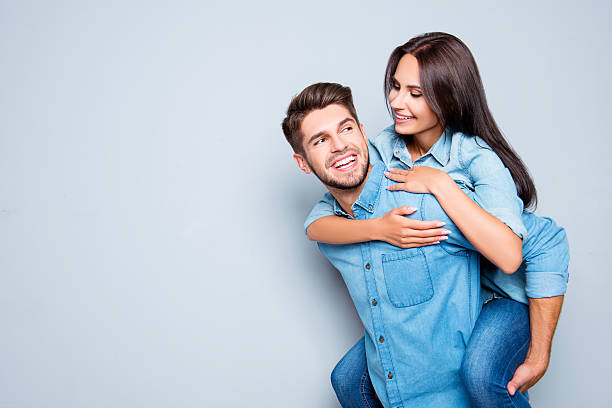 Happy  man carrying his girlfriend on the back Happy  man carrying his girlfriend on the back on gray background boyfriend stock pictures, royalty-free photos & images