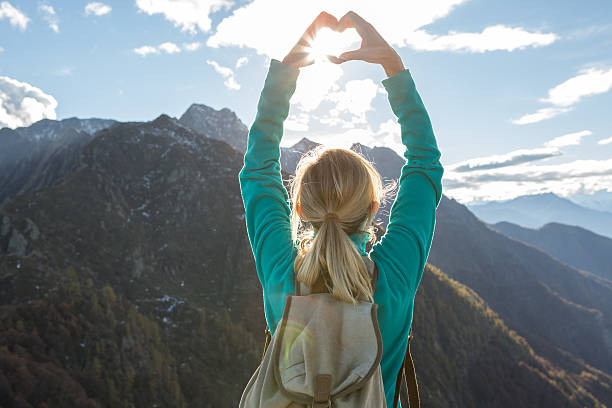 istock Young woman hiking on mountain top makes heart shape frame 637411258