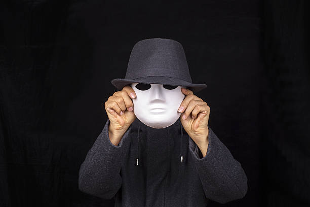 hand holding mask and wearing fedora hat