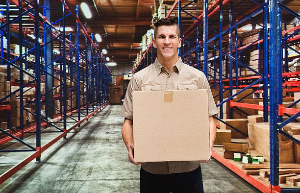 istock Smiling worker standing in warehouse with box 637411858
