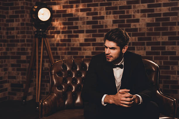 istock Young rich businessman in black suit sitting on leather sofa 637412008