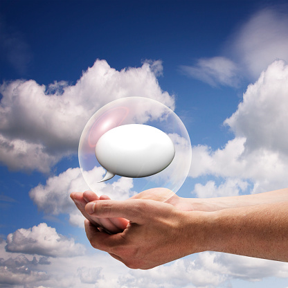 A square composite image of a pair of adult male hands holding a speech bubble within a bubble, against a blue sky.
