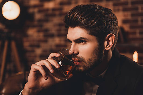 porträt von sexy jungen stattlichen mann trinken cognac - smoking issues fotos stock-fotos und bilder