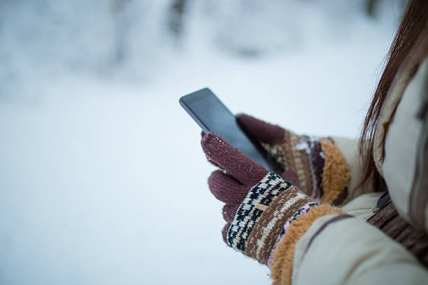 istock Female hands holding a cellphone outdoors in the snow 637415812