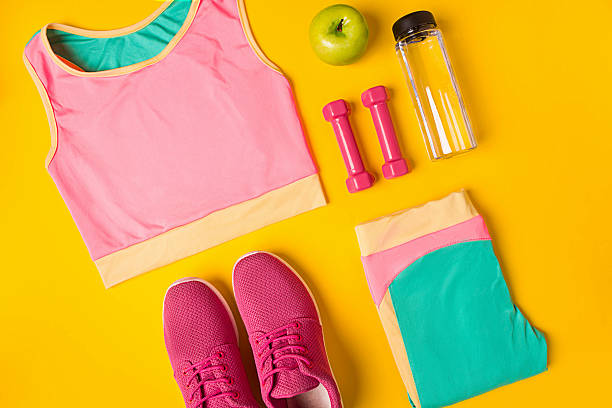 Top view, flat lay. Mockup. Sports and fitness background. Still life of bottle with water, sportswear, dumbbells, apple on yellow background. Top view, flat lay. Mockup Sports and fitness background. sportswear stock pictures, royalty-free photos & images