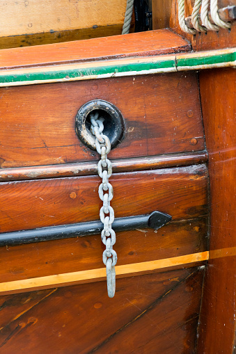 Hawsehole with anchor chain at an old wooden barge.