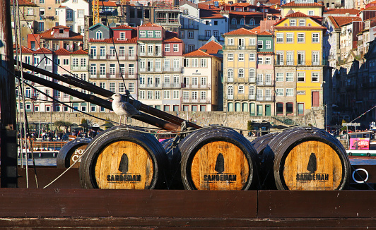 Porto, Portugal - December 28, 2016: Three barrels of port wine Sandeman on a boat. The town of Porto as a background.
