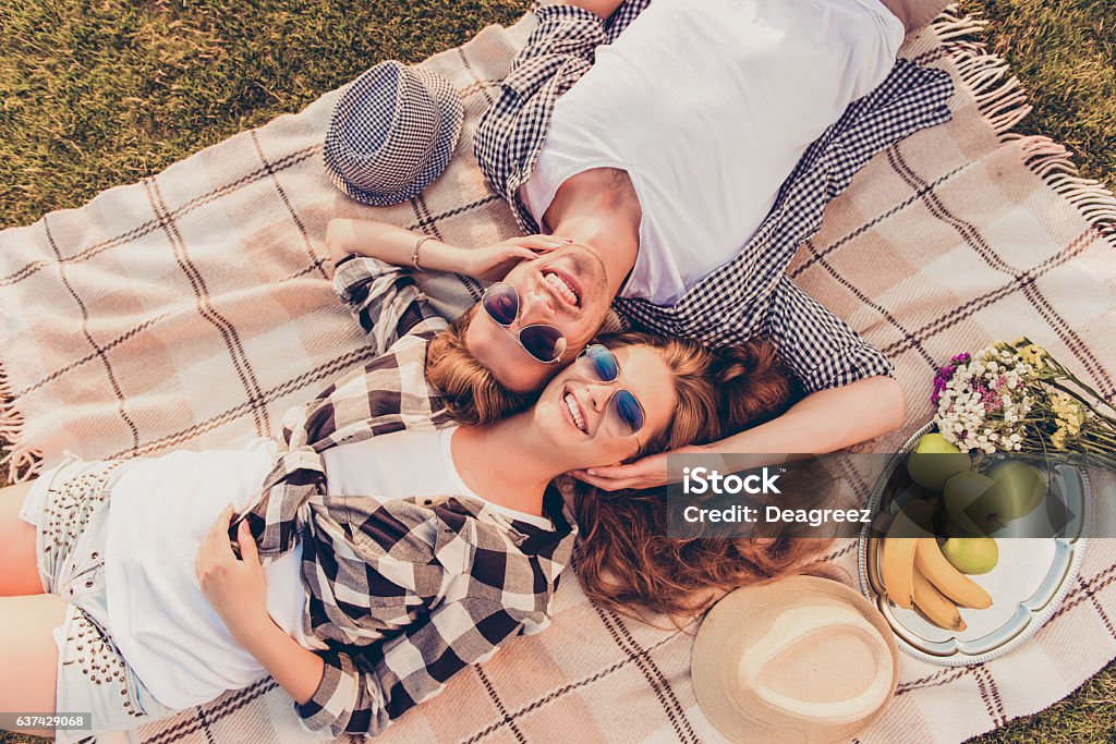 top-view of a couple in love lying on picnic plaid top view of a couple in love lying on a picnic plaid Summer Stock Photo