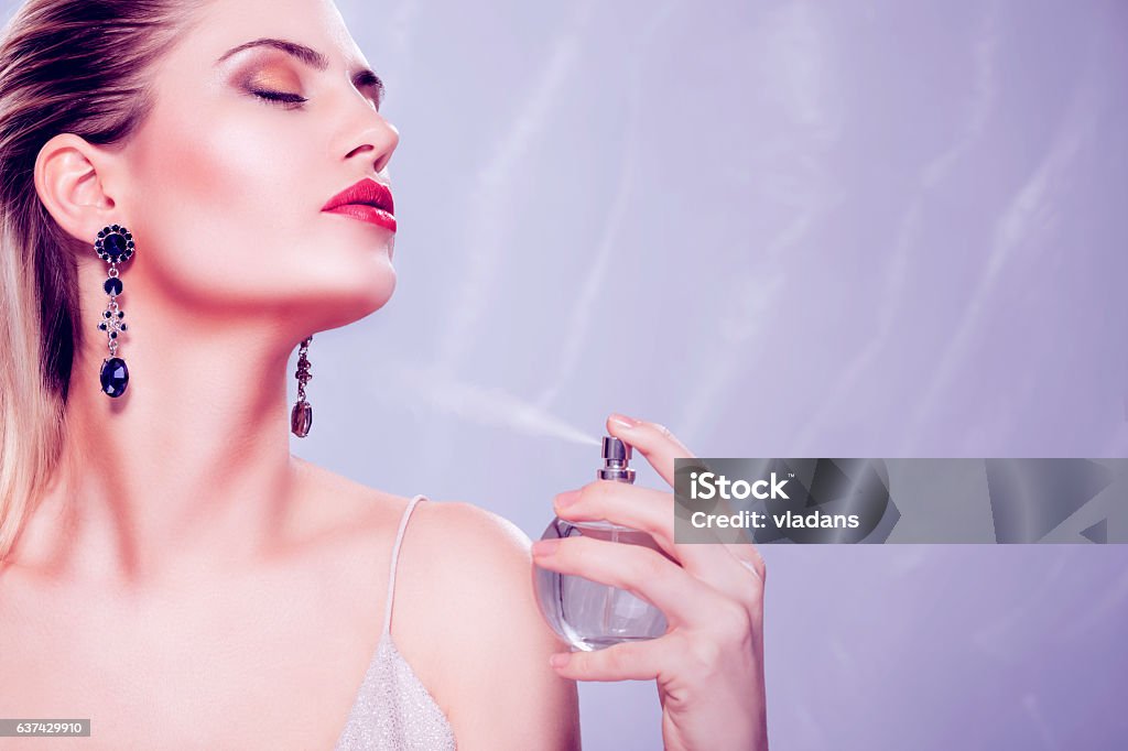 Beauty portrait Beautiful seductive woman holding a perfume bottle and applying it Perfume Stock Photo