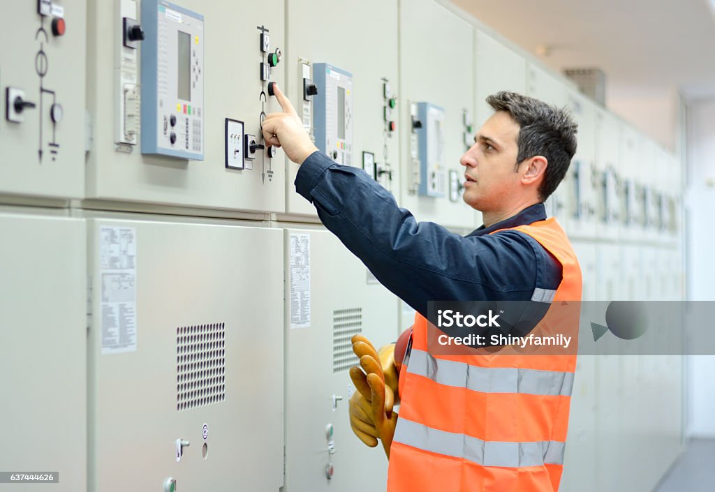 Industrial Technician Operating in Power Substation Electrician working in electrical cabinet. Manual worker have safety equipment. Engineer Stock Photo