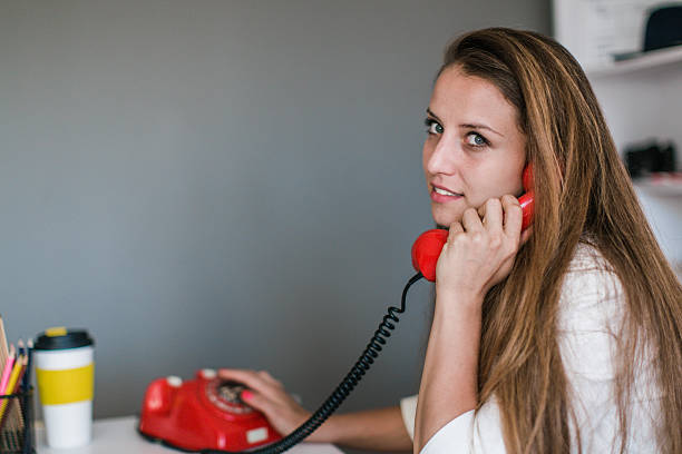 istock Beautiful young woman working on computer and talking on phone 637458178