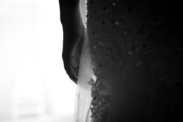 Black and white of a brides hand hanging next to her hip