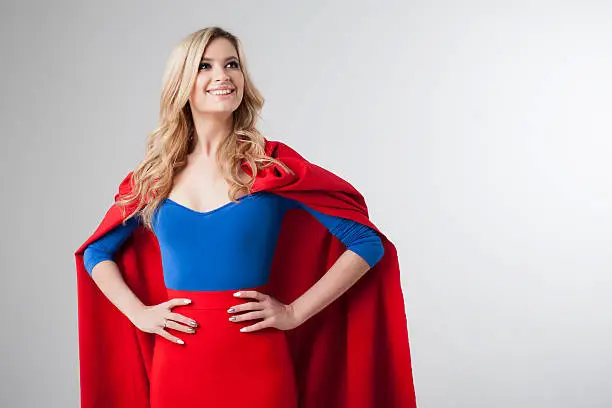 Superhero Woman. Young and beautiful blonde in the image of a superheroine in a red Cape growing