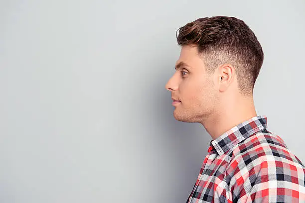 Profile of handsome smiling young man on gray background