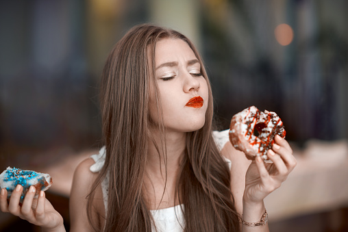 eating sweets, woman portrait craving for delicious donuts, tasting it and feeling very good.