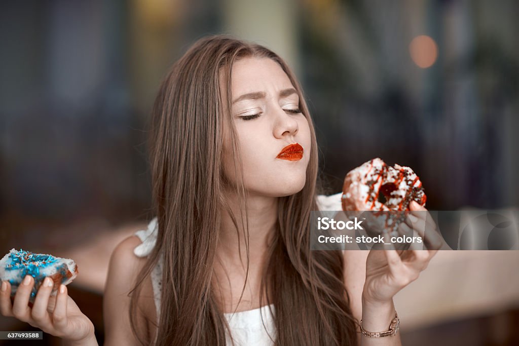 tasting delicious donuts eating sweets, woman portrait craving for delicious donuts, tasting it and feeling very good. Eating Stock Photo