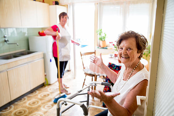 Caregiver Doing the Chores Elderly Woman talking with a caregiver while she is doing chores cleaning equipment photos stock pictures, royalty-free photos & images