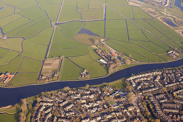 Dutch landscape with village, green fields and canal Aerial view of a village separated from green fields by a canal, The Netherlands netherlands aerial stock pictures, royalty-free photos & images