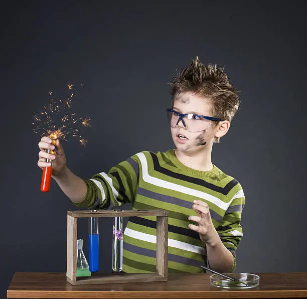 Photo of Funny little boy performing experiments. Crazy scientist. Education background.