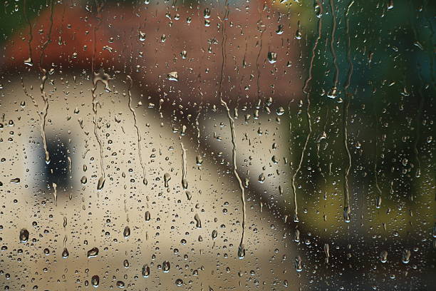 istock Rain drops on window with house and church in background 637513402