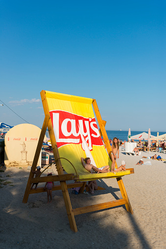 Odessa, Ukraine - September 7, 2016: People lounge in a giant Lay's chair at the beach in Odessa, Ukraine