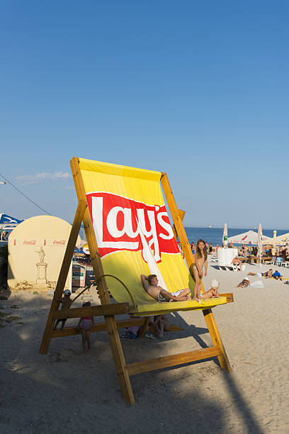 Beach life in Odessa, Ukraine Odessa, Ukraine - September 7, 2016: People lounge in a giant Lay's chair at the beach in Odessa, Ukraine lays potato chips stock pictures, royalty-free photos & images