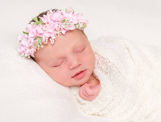 istock cute newborn in headband with flowers smiling asleep 637517046