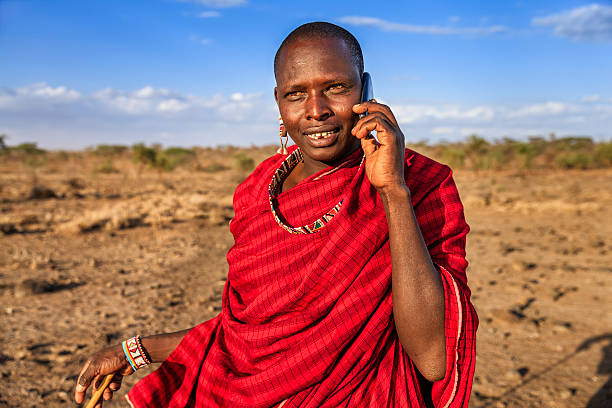 Warrior from Maasai tribe using mobile phone, Kenya, Africa African warrior from Maasai tribe using mobile phone, central Kenya, Africa. Maasai tribe inhabiting southern Kenya and northern Tanzania, and they are related to the Samburu. kenyan man stock pictures, royalty-free photos & images