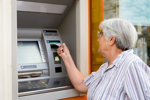 elderly woman inserting credit card to ATM