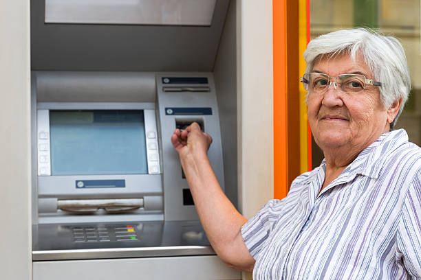 istock elderly woman inserting credit card to ATM 637525084