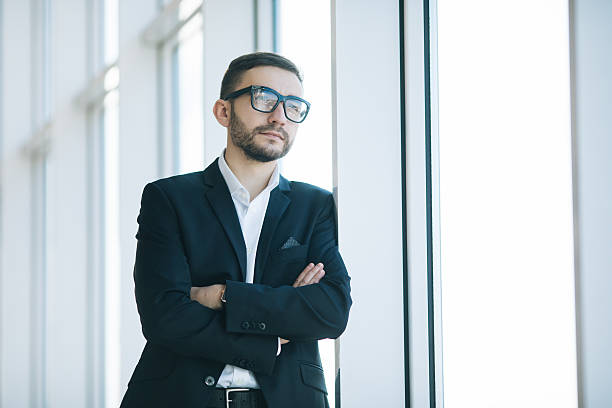 istock Handsome businessman in suit and eyeglasses on windows background 637525892