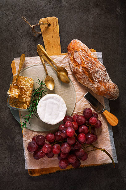 cheese with grapes on cutting board with honey and bread