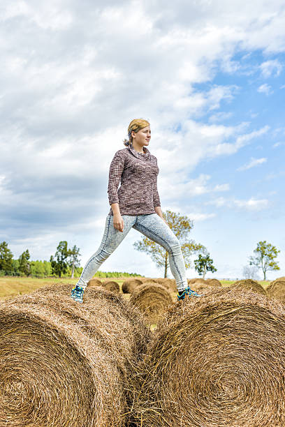 istock Young woman balancing on hay roll bales 637527968