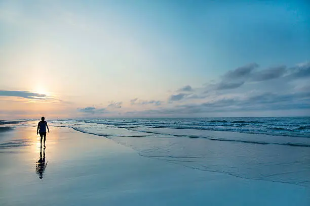 Photo of Man walking on beach at sunrise