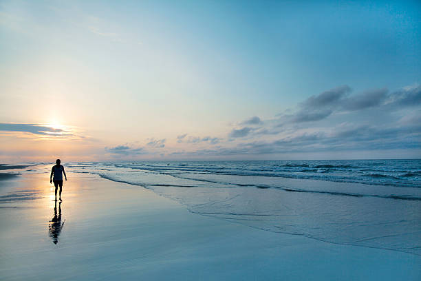 człowiek spaceru na plaży w sunrise - walking loneliness one person journey zdjęcia i obrazy z banku zdjęć