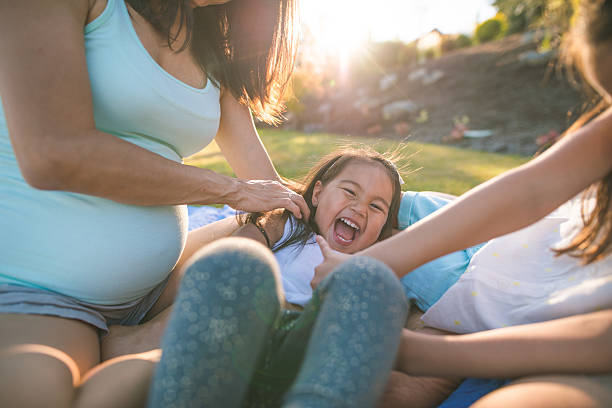 Little girl and mother with inflateable raft being splashed by waves in sea. Candid smile and laugh of a cute little girl having fun with her mother.