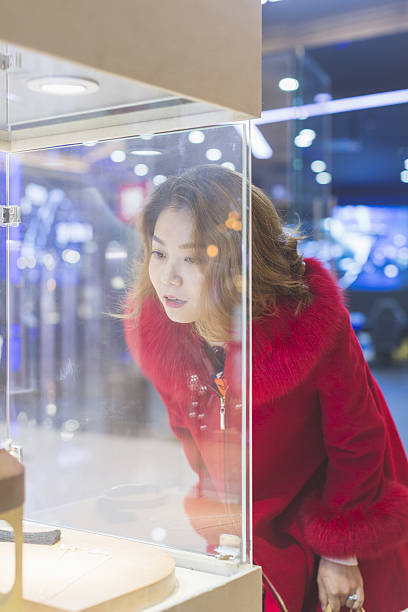 jeune femme regardant des bijoux à travers la vitrine - shopping jewelry chinese ethnicity asian ethnicity photos et images de collection