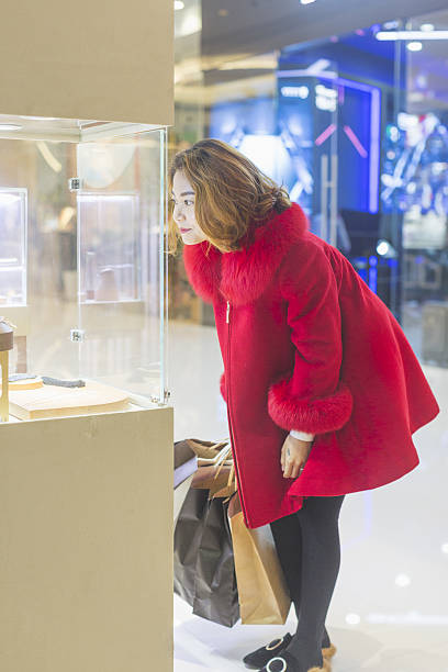 jeune femme regardant des bijoux à travers la vitrine - shopping jewelry chinese ethnicity asian ethnicity photos et images de collection