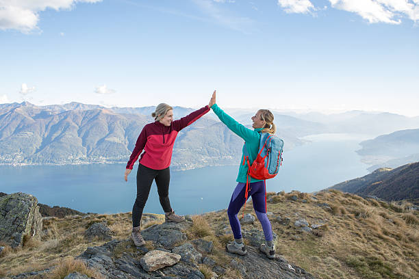 Couple of hikers reaching the mountain top celebrating with a high five.