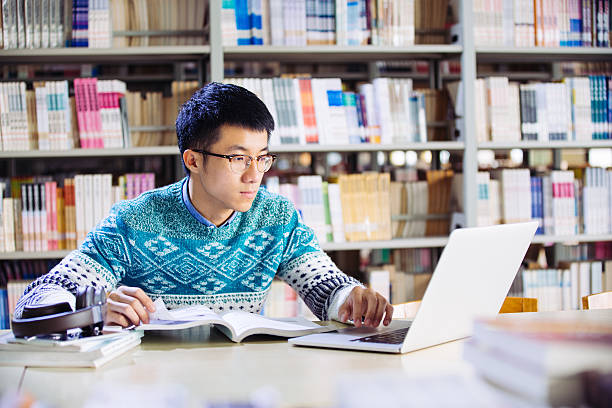 istock young asian man with laptop in library 637538098