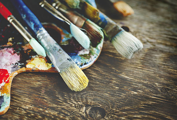 istock Artist paint brushes and palette on wooden background. 637540728