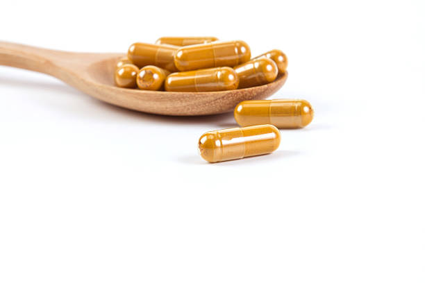 Close up turmeric capsule in spoon on white background