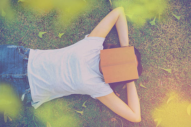 istock young woman lying on a lawn with a book. 637548740