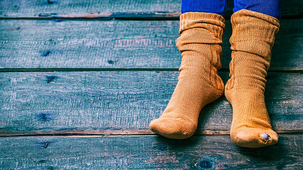 Worn out socks Female feet wearing worn out brown wool socks on the wooden floor. Closeup view hole in pants stock pictures, royalty-free photos & images