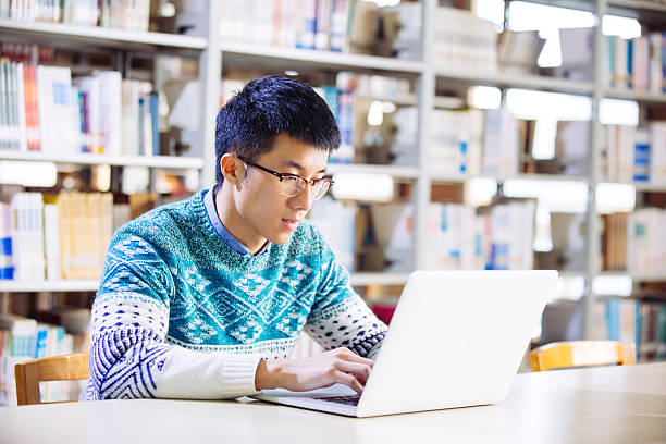 istock young asian man with laptop in library 637554704